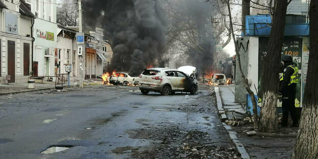 Brennende Autos in einer zerstörten Straße
