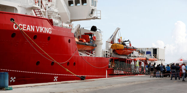 Rotes Schiff Ocean Viking im Hafen von Pozalla, im Hintergrund stehen Flüchtlinge und Helfer auf dem Kai.