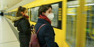 Zwei Personen mit Maske vor einer U-Bahn