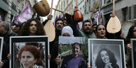 Menschen auf der Straße halten bei einer Demonstration Portraitfotos und Musikinstrumente hoch