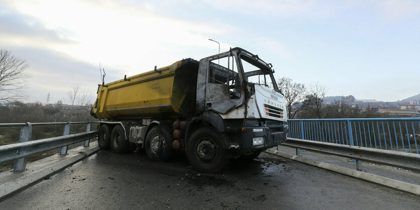 Ein großer ausgebranter LKW blockiert eine Straße