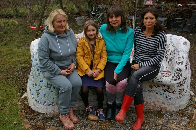 Drei Frauen und ein Mädchen auf einem Sofa im Garten