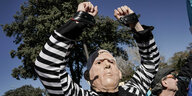 Ein Mensch und Sträflingskleidung und Netanjahu Maske, hebt die Handschellen und protestiert