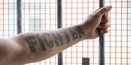 "Fighter" ("Kämpfer") steht auf dem Arm eines Insassen, der vor einem vergitterten Fenster in der Unterbringungseinrichtung für Ausreisepflichtige (UfA) der Bezirksregierung Detmold steht