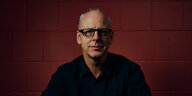 Porträt von Greg Graffin vor rotem Hintergrund
