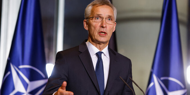 Jens Stoltenberg im Anzug vor Nato-Flaggen bei einem Treffen mit Olaf Scholz am 1. Dezember