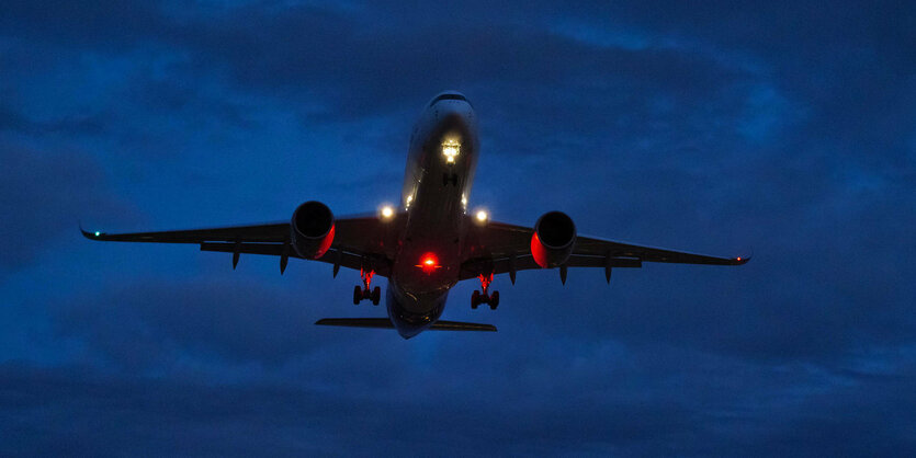 Ein landendes Flugzeug vor dunklem Himmel