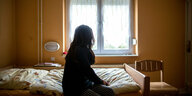 Eine Frau sitzt in einem Frauenhaus auf einem Bett