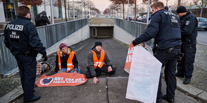 Kli­ma­ak­ti­vis­t:in­nen sitzen vor der Tiefgarage des Bundestags