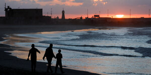 Menschen am Meer vor einem Sonnenuntergang