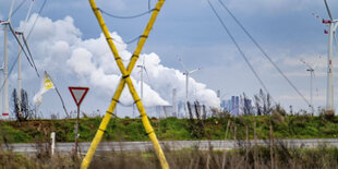 Ein gelbes X markiert das Camp der Klimaaktivisten in Lützerath, im Hintergrund qualmen Schornsteine in der sonst friedlichen Landschaft