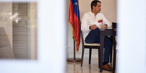 Interimspräsident Juan Guaidó sitzt neben der venezonalischen Flagge