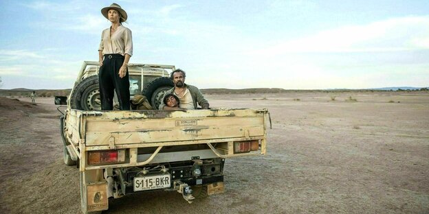 A truck with three people in the middle of the Australian outback