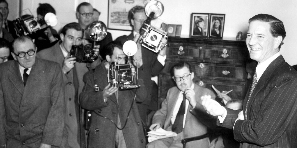 Ein Mann im Anzug spricht vor Journalisten und Fotografen