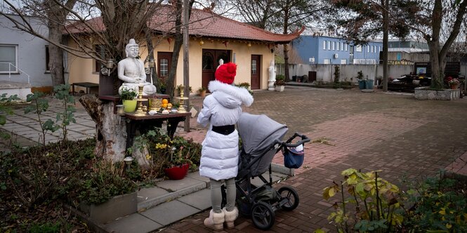 Eine Frau betet vor Altar mit Buddhastatue vor der Berliner Pho-Da-Pagode