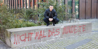 Auf dem Bild ist der Hamburger Rapper Disastar auf zu sehen. Er hockt auf einer Mauer mit dem Schriftzug "nicht mal das Mindeste"