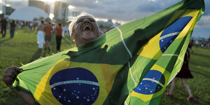 Eine Person feiert mit einer brasilianischen Fahne
