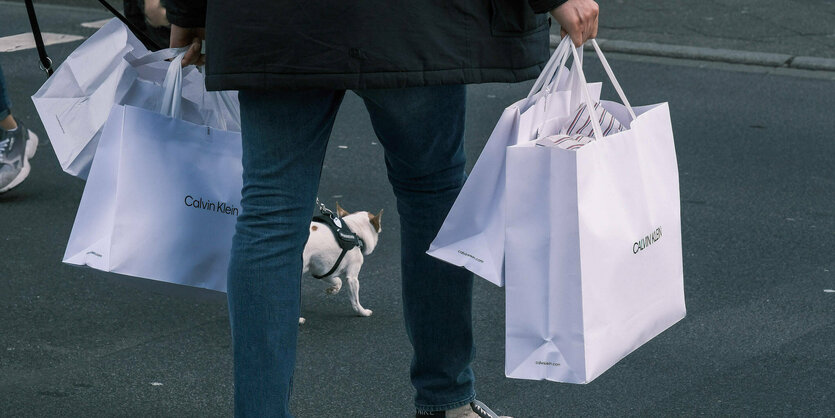 Eine Person mit Einkaufstüten überquert eine Straße