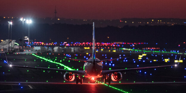 Ein Flugzeug landet am späten Abend auf einem beleuchteten Rollfeld