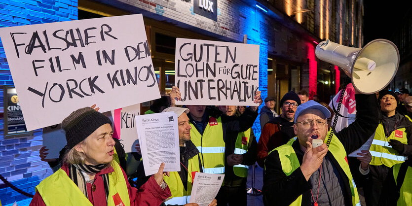 Menschen stehen mit Plakaten vor einem Kino