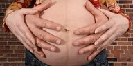 Schwangerer Bauch wird von 4 Händen umfasst