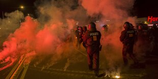 Polizisten gehen durch Rauchwolken