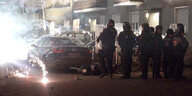 Polizeibeamte in Neukölln stehen hinter explodierendem Feuerwerk.