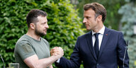 Wolodimir Selenski und Emmanuel Macron sehen sich in die Augen und reichen sich die Hand