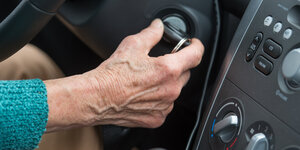 Eine Hand dreht den Anlasser-Schlüssel eines Autos