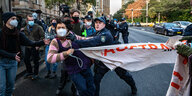 Ein Polizist drückt eine Frau mit einem Transparent zur Seite
