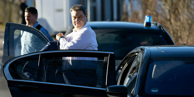 Söder steigt aus einem schwarzen Auto, im Begriff sich sein Jackett anzuziehen