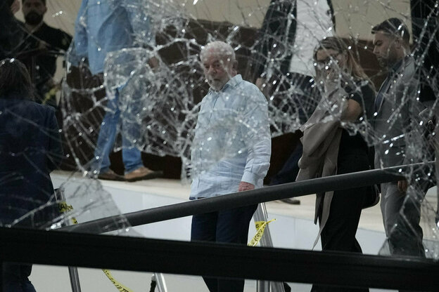 Brasiliens Präsident Lula blickt auf eine kaputte Fensterscheibe.