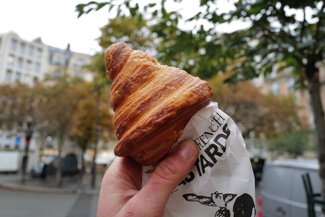 Eine Hand hält ein weiteres Croissant auf einer Straße in Paris