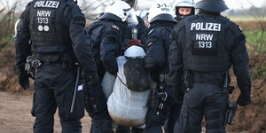 Polizist:innen tragen eine:n Klima-Aktivist:in in Lützerath weg
