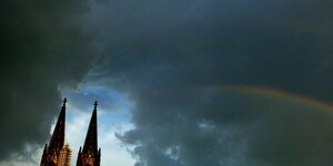 Kölner Dom mit dunklem Himmel und Regenbogen