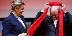 Franziska Giffey übergibt Olaf Scholz einen roten Schal