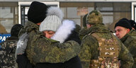 Ein russischer Soldat und eine Frau umarmen sich zum Abschied in den Krieg