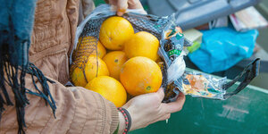 Eine Person hält einen Beutel Orangen in den Händen