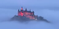 Die Burg Hohenzollern ragt aus dem Nebel hervor.