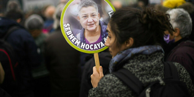 Eine Frau hält ein Schild in der Hand, darauf abgebildet ist Şebnem Korur Fincancı
