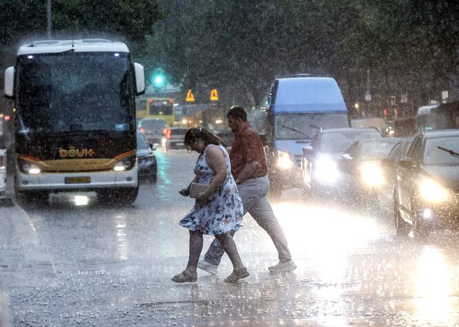 Mann und Frau in sommerlicher Kleidung queeren bei strömendem Regen eine Straße