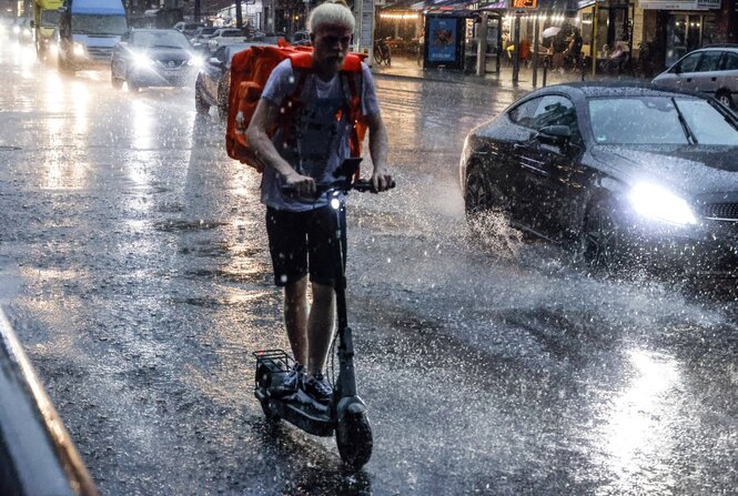 E-Scooter-Fahrer im Regen auf Berliner Straße