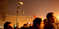 Viele Menschen bei Protesten, eine Person mit Fahne auf einem Laternenmast