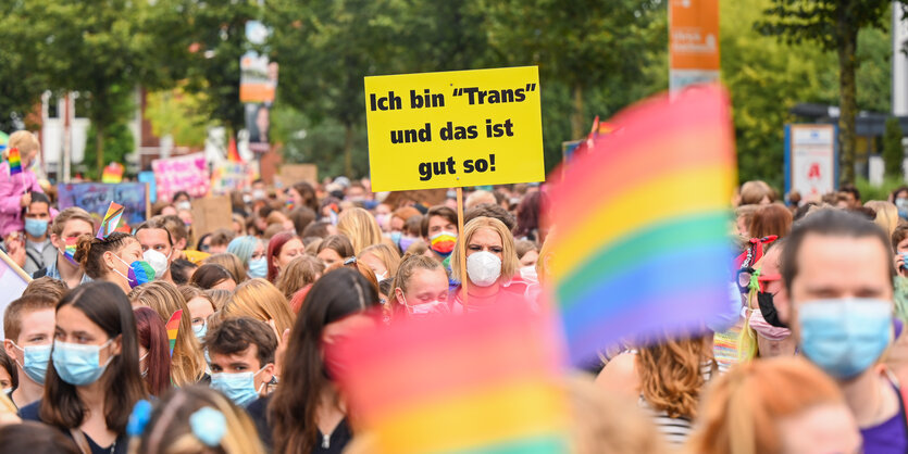 Menschen auf einer Demo. Auf einem Plakat steht: Ich bin "trans" und das ist gut so