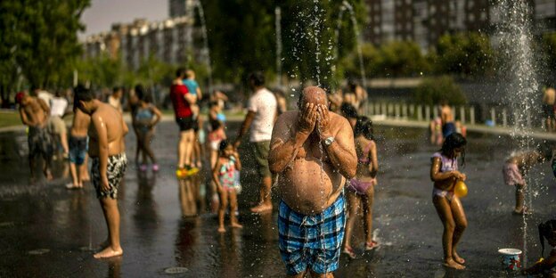 People on the street who let themselves be splashed by water fountains in bathing suits