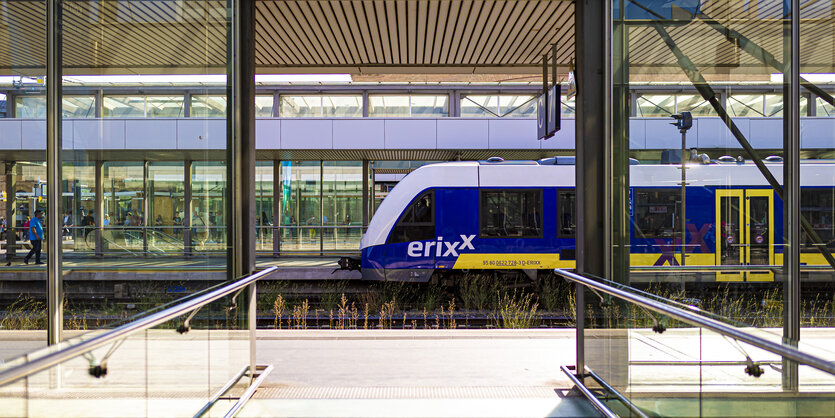 Ein Zug in Blau und Gelb steht an einem Bahnhof auf einem Gleis