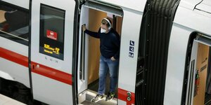 Ein Mann, der eine FFP2-Maske trägt, steht an der offenen Tür eines ICEs