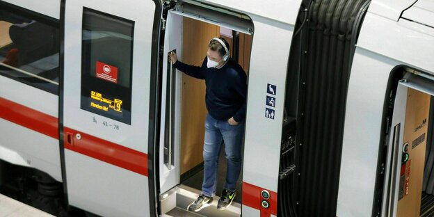 A man wearing an FFP2 mask stands at the open door of an ICE
