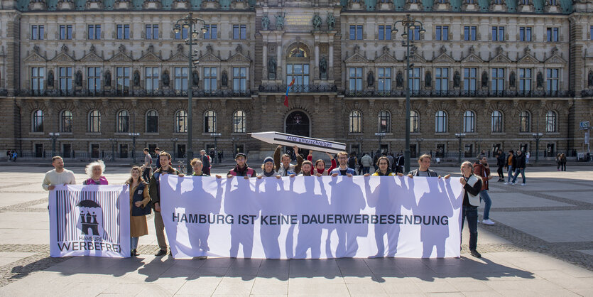 Menschen halten auf dem Rathausmarkt ein Transparent, auf dem steht: "Hamburg ist keine Dauerwerbesendung"