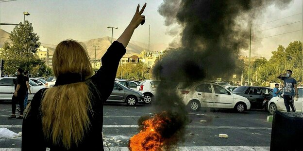 Demonstranten stehen vor einem brennenden Autoreifen